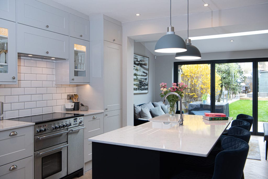 White kitchen with an island overlooking a garden White kitchen with an island overlooking a garden